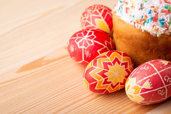 Celebration Easter in Ukraine. Inked eggs near Paska(traditional Easter bread in Ukraine) on light wooden table with copy space