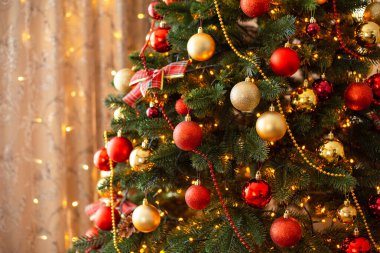 Warm bright lights of garland, festive interior, beautiful christmas tree with round baubles. Winter decoration, new year and christmas time