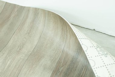 Covering concrete floor with linoleum with wooden structure. Unroling linoleum