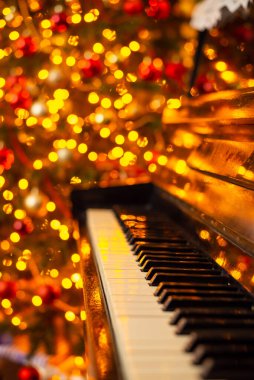 Piano keyboard and bright lights of electric garland on the background. Celebration of Christmas, festive atmosphere at home