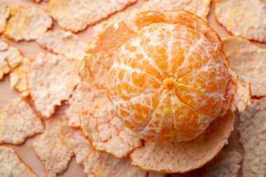 Top-down view of peeled tangerine with peel around. Ripe tasty tangerine