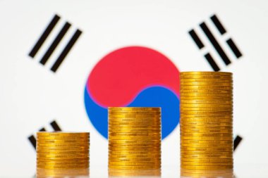 Three stacks of golden coins on the background of flag of South Korea. Rise of economy of the country