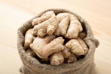 Bag with ginger root on wooden table. Harvest of ginger, spice for tea
