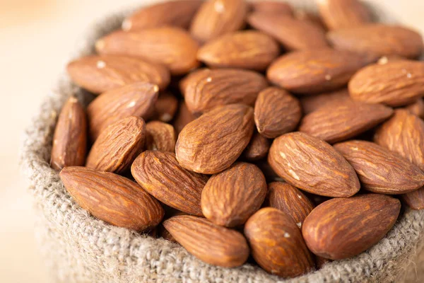 Small linen bag with almonds, close up. Macro shot of fresh tasty almond nuts in bag