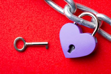 Violet heart lock on steel chain and small key. Concept of love, relationships