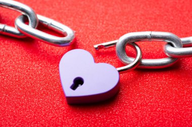 Lock releases two pieces of chain. Concept of end of love, relationships. Small lock in shape of a heart opens, symbolising end of love