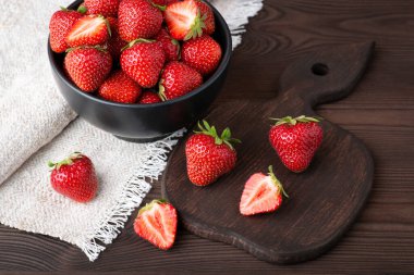 Bowl of fresh red strawberries on black wooden table. Studio shot of strawberry