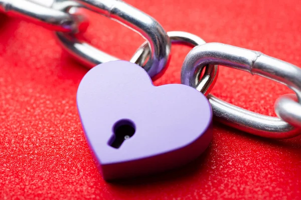 Lock in shape of a heart holding two pieces of chain together. Concept of love holding two people together