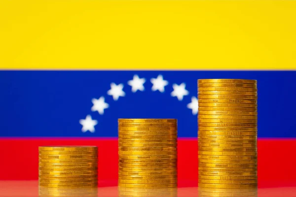 Stacks of golden coins with flag of Venezuela on the background. Financial development of Venezuela, economy growth, increase of GDP rate concept
