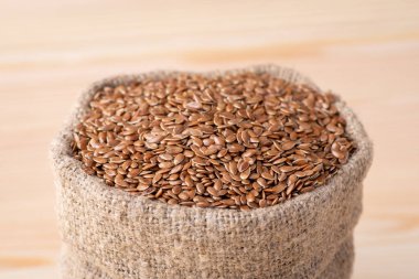 Linen grain in bag against wooden background. Linen grain used for adding in bakery clipart