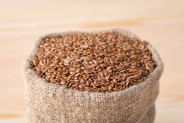 Linen grain in bag against wooden background. Linen grain used for adding in bakery