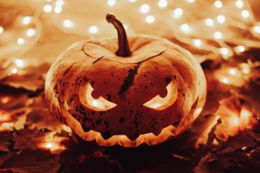 Jack-o-lantern with bright candle light inside. Halloween theme, warm golden colours, pumpkin as a symbol of autumn holiday