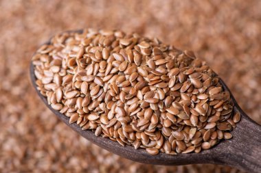 Linen grain in wooden spoon. Macro detail shot of linen grain in dark wooden spoon