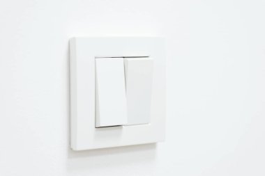 White light switch on white wall. One part of switch is turned on, the other is turned off