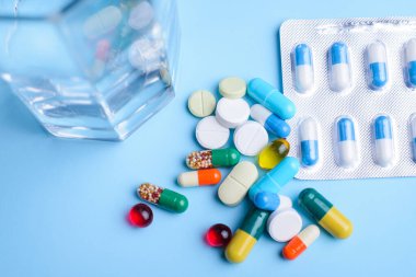 Top view of medicine on the blue table before taking them by ill or sick person. Big daily dose of pills and capsules for treatment difficult cases of diseases