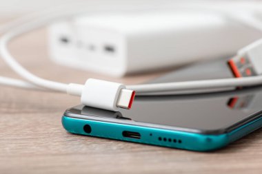 Close up shot of mobile phone and usb Type C connector on the table, powerbank on the background. Fast charging of modern devices, up-to-date technologies concept