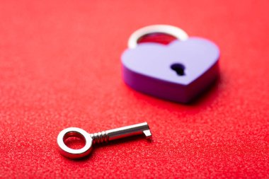 Close up of small violet lock in shape of heart and a key. Concept of love