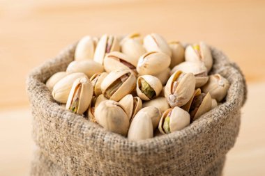 Close up of small linen bag with pistachios. Tasty salted pistachios