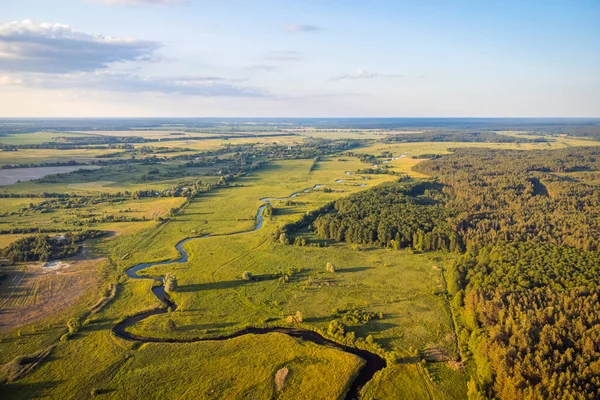 Stunning aerial view of a small river and forest nearby. Spectacular summer landscape, blue sky, warm light