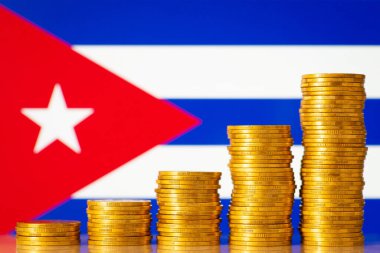 Stacks of bright gold coins near flag of Cuba. Development of economy of Cuba concept