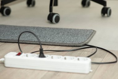 Electric warming mat near office chair for heating white working on the computer. Electric mat on the floor