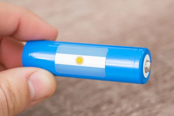 Li-ion battery with flag of Argentina in mans hand. Production of batteries in Argentina concept