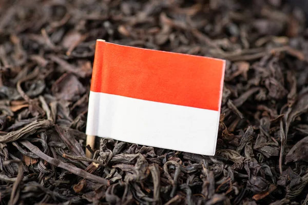 Flag of Indonesia between black tea leaves close up. Growing tea in China concept