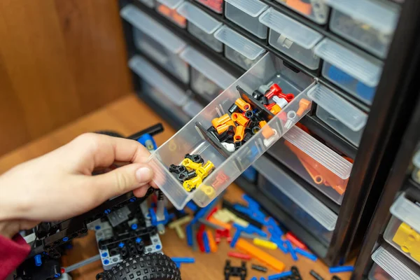 stock image Hand of a boy taking constructor detail from the shelf with different parts. Playing with modern scientific constructor, building models