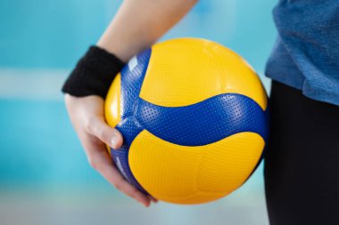 Spor salonunda duran bir kadın oyuncunun elinde voleybol. Topu bir öğrencinin, eğitimin ve ustalaşma becerilerinin ellerine bırak.