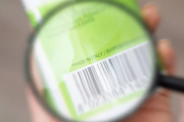 stock image Tube of shampoo with Made in Italy inscription in man's hand, close up. Inscription on product package under magnifying glass, manufacturing and trade concept