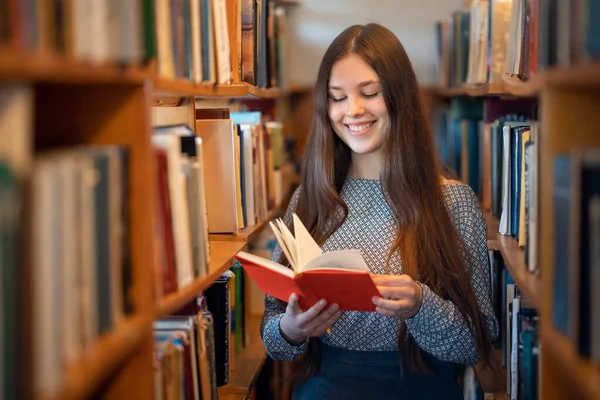 Χαρούμενη Φοιτήτρια Που Στέκεται Ανάμεσα Ράφια Βιβλιοθηκών Στη Βιβλιοθήκη Του — Φωτογραφία Αρχείου