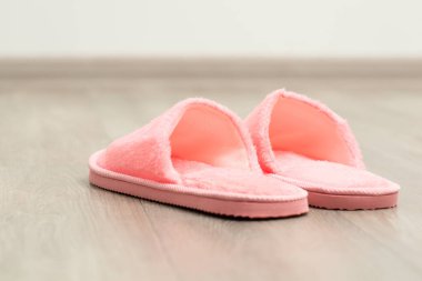 Pembe ev ayakkabıları yerde. Odada pembe renkli terlikler var.