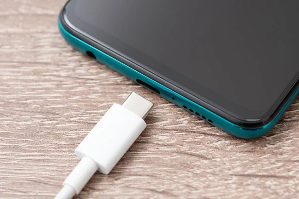 Close up of usb type-c cable near mobile phone. Connecting usb c cable to the phone for charging