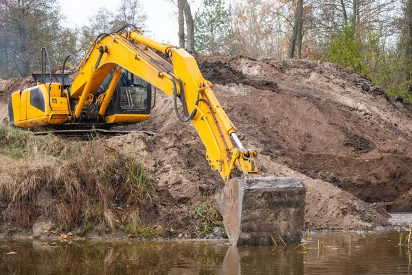 挖掘机挖掘人工水盆 挖掘机的长臂伸展池塘的堤岸 使之变得更大 — 图库照片