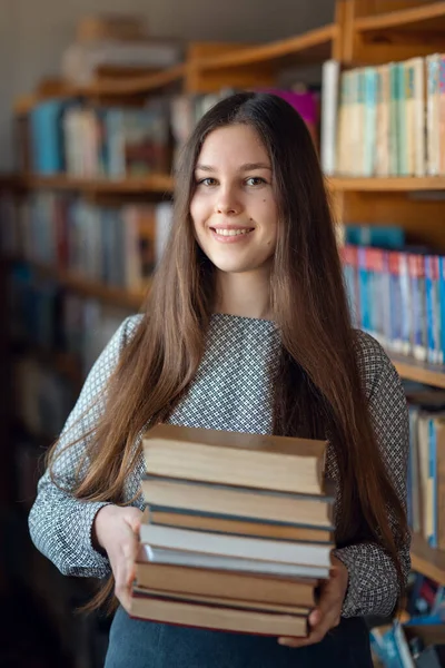 本の山を持つ図書館の少女学生の肖像画 図書館から本を取って勉強する女子学生 — ストック写真