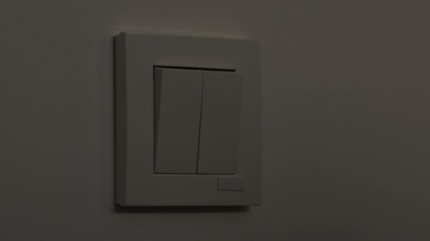 男人打开房间里的灯 墙上有两个开关 在黑暗的房间里打开灯 人造光源 — 图库视频影像