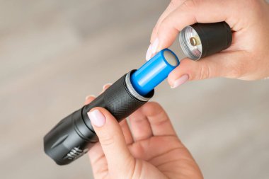 18650 bataryasını el fenerine yerleştiriyorum, kapatın. Kadınların elinde karanlıkta ışık tutmak için küçük taşınabilir cep aygıtı