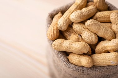 Ahşap arka planda fıstıklı çanta. Soyulmamış fıstıklara yakın çekim, fındık hasadı