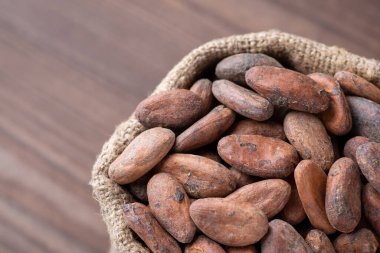 Kakao fasulyesi keten çuvalında, siyah ahşap masaya karşı. Toplanan kakao fasulyeleri.
