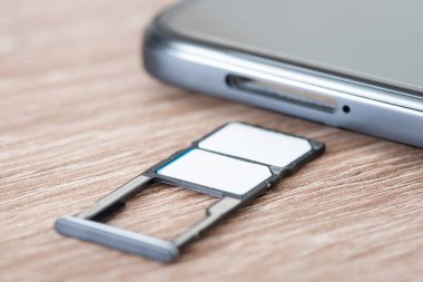 Akıllı telefonlara yerleştirilen farklı cep telefonu operatörlerinin Sim kartları. Masanın üzerinde iki sim kartı olan cep telefonu sehpası
