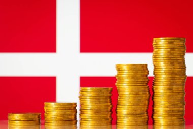 Danimarka bayrağına karşı beş yığın altın para yükselen tabloyu oluşturuyor. Ekonomik kalkınma, tasarruf, Danimarka 'da yaşam düzeyi