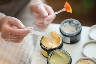 Profesyonel bir kozmetolojistin farklı spa maskelerini farklı efektlerle alıp birleştirdiği elleri. Profesyonel nemlendirici, temizleyici, parlatıcı, deri yüzücü maskeli cilt bakımı