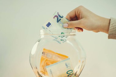 Kadın cam kavanoza 20 Euro koyuyor. Bir rüya için para biriktiriyorum, tonlu fotoğraf için.