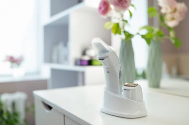 Odaklanmamış çiçek ve rafların arkasındaki yüzü ultrasonik olarak temizlemek için bir cihaz. Kozmetolojide spa prosedürleri için profesyonel tıbbi araç