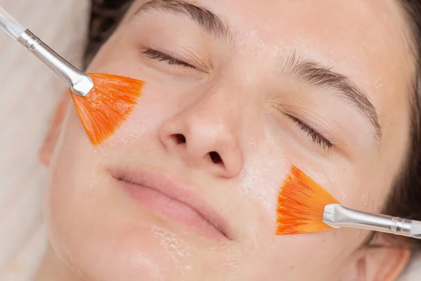 İki fırça yardımıyla genç kızların yüzüne jöle soyuyorlar. Güzellik salonu, cilt bakımı ve kozmetoloji spa konseptinde profesyonel prosedür