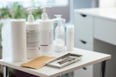 Güzellik salonundaki beyaz masada deri temizlemek için kozmetoloji jelleri, kremler ve metal aletler. Güzellik kliniği, profesyonel sağlık ve cilt bakımı kavramı