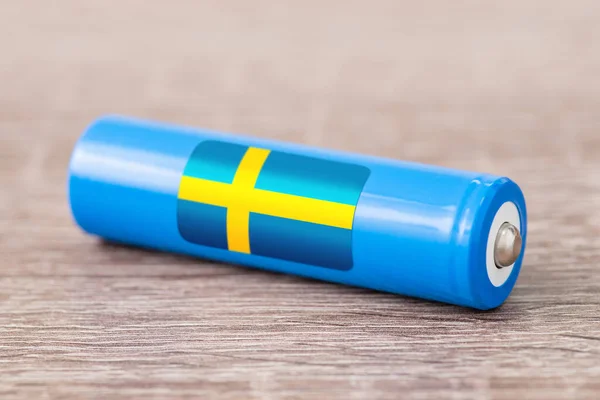 Rechargeable battery with flag of Sweden on table. Origin of battery, produce accumulators in Sweden