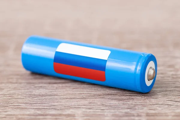 Rechargeable battery with flag of Russia on table. Origin of battery, produce accumulators in Russia