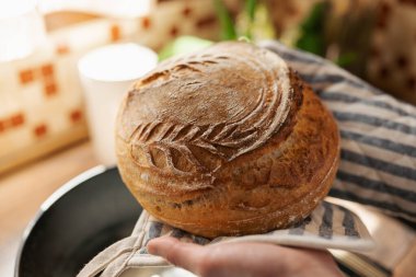 Pişmiş ekmeği olan bir ev sahibesinin elleri. Ev kavramında ekmek pişirmek