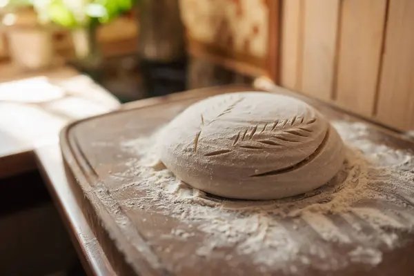 Ready for baking bread dough in flour, ornate with patterns. Baking bread at home, kitchen background